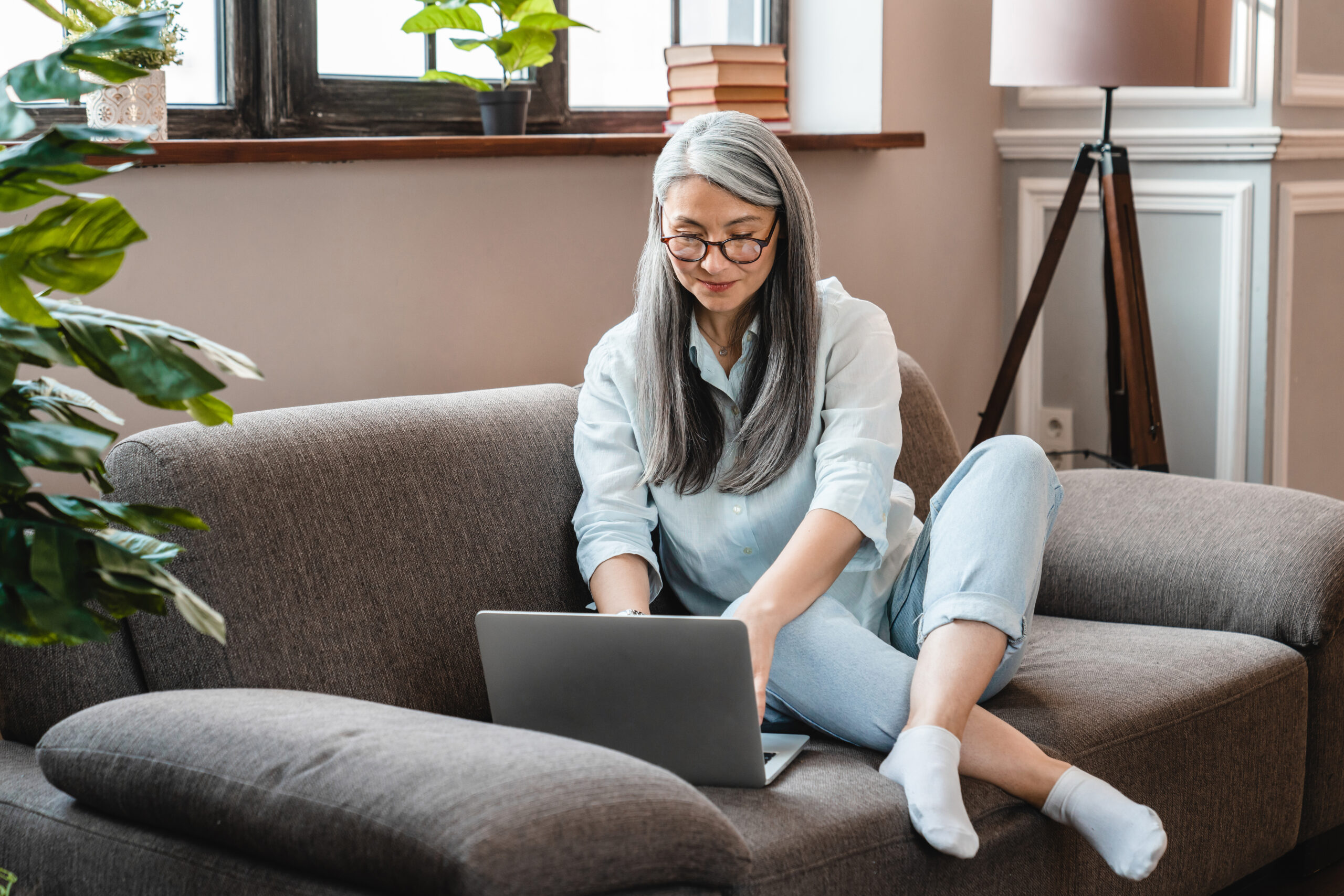 Attractive middle-aged caucasian woman using laptop on the sofa